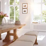 Un tavolo in legno massiccio con un mazzo di tulipani rosa e una **finestra alla francese** che inonda la stanza di luce solare.