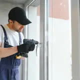 Operaio con trapano effettua la trasformazione finestra in portafinestra, pratica CILA o SCIA.