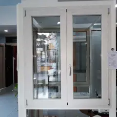 Finestra con telaio in alluminio effetto legno, con doppio vetro e maniglia argentata. Sullo sfondo, porte e altre finestre.