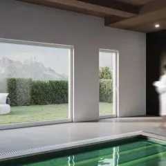Interno moderno con piscina, grandi vetrate che incorniciano montagne e giardino, e infissi in legno lamellare che creano un'atmosfera calda.