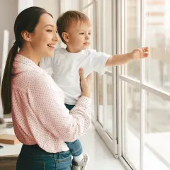 Mamma e bambino guardano fuori dalla finestra. Un giorno, potremo rifare gli infissi a costo zero e godere di una vista ancora più bella.