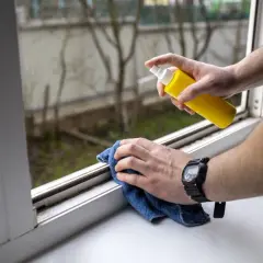 Come togliere la colla dagli infissi in alluminio: spruzzare un detergente su un panno blu e pulire il davanzale.