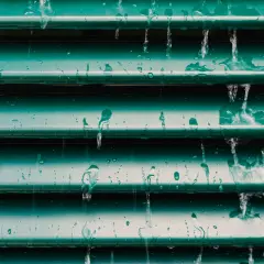Acqua che scorre su persiane verdi, un esempio visivo per capire come pulire le persiane in ferro.