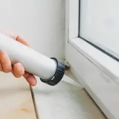 Applicazione di silicone per come isolare finestre vecchie in alluminio. Sigillatura del telaio per migliorare l'efficienza energetica.