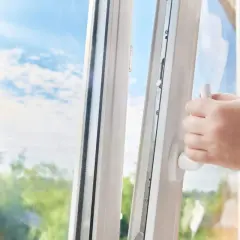Mano che apre una finestra a ribalta o vasistas, lasciando entrare l'aria fresca e la luce del sole.