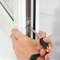 Mano che regola il nottolino di una finestra con un cacciavite.
