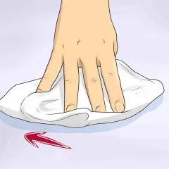 Mano che pulisce una superficie con un panno bianco, mostrando come togliere graffi dal vetro con un movimento circolare.