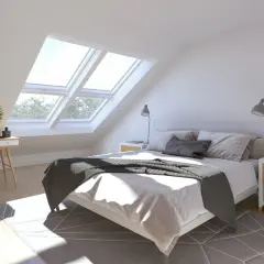 Luminosa camera da letto con finestre sul tetto che inondano di luce naturale il letto accogliente e la zona toeletta.