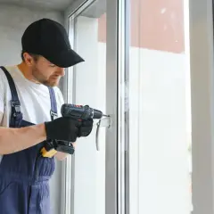 Operaio con trapano effettua la trasformazione finestra in portafinestra, pratica CILA o SCIA.