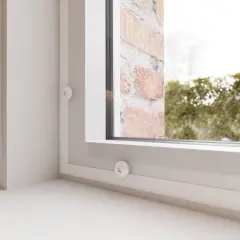 Dettagli di un sistema per come isolare le finestre dal freddo, con piccoli dischi bianchi fissati sul telaio.