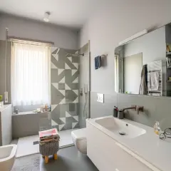 Bagno moderno con doccia su finestra, lavabo, bidet e scalda-asciugamani.