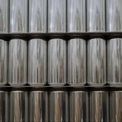 Fila di lattine d'alluminio argentate impilate. Sorprendentemente, l'alluminio è magnetico, anche se non in modo evidente come il ferro.