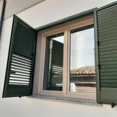 Infissi PVC effetto legno, colori naturali per un'estetica calda e moderna. Le persiane verdi si integrano perfettamente.