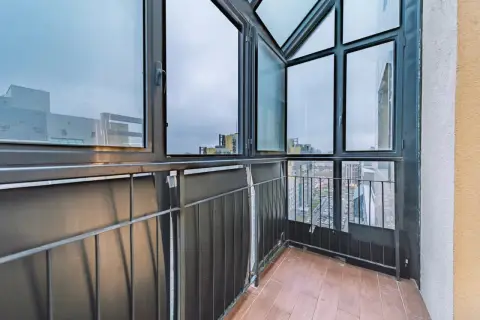Balcone con vista sulla città, caratterizzato da ampie finestre con infissi neri che incorniciano il panorama urbano.