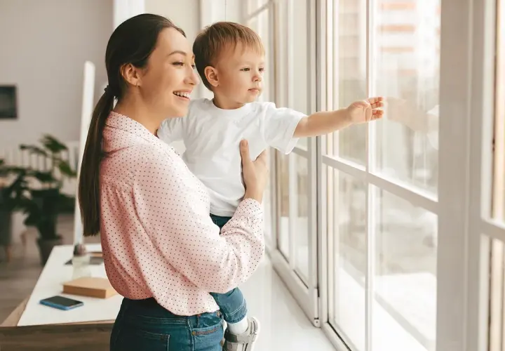 Mamma e bambino guardano fuori dalla finestra. Un giorno, potremo rifare gli infissi a costo zero e godere di una vista ancora più bella.