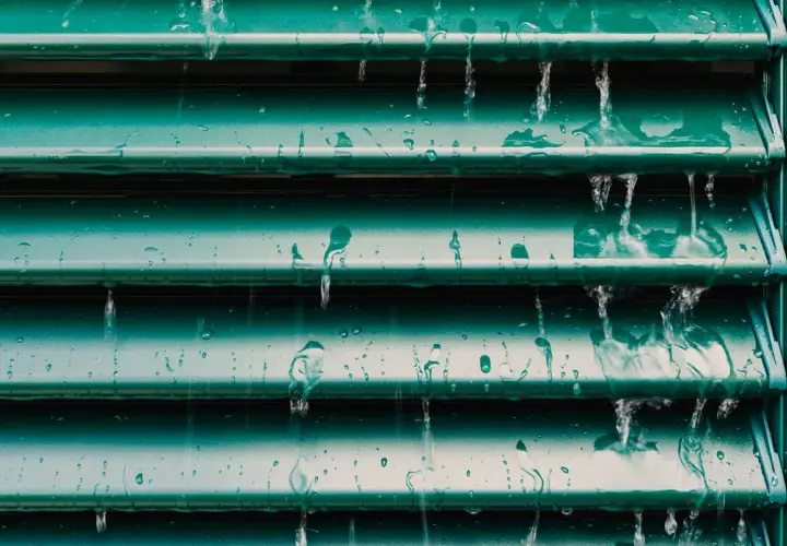 Acqua che scorre su persiane verdi, un esempio visivo per capire come pulire le persiane in ferro.