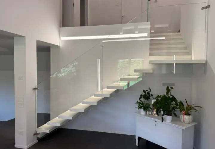 Moderna scala a sbalzo con parapetto in vetro, illuminazione integrata e un'elegante balaustra. Perfetta per il vano scale di una villa moderna.
