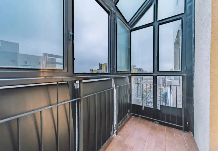 Balcone con vista sulla città, caratterizzato da ampie finestre con infissi neri che incorniciano il panorama urbano.
