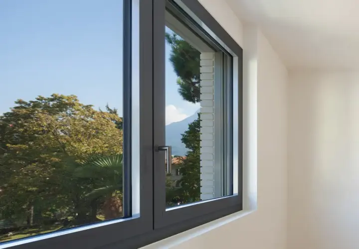 Finestra in alluminio con vista su alberi e montagne. Utile per chi cerca come regolare vecchi infissi in alluminio.