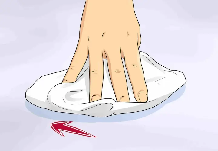 Mano che pulisce una superficie con un panno bianco, mostrando come togliere graffi dal vetro con un movimento circolare.