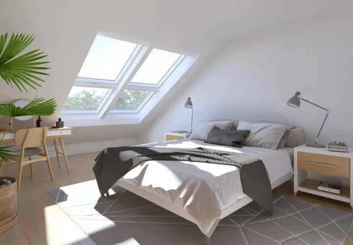 Luminosa camera da letto con finestre sul tetto che inondano di luce naturale il letto accogliente e la zona toeletta.