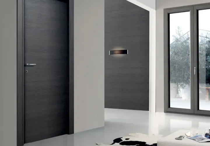 Porta moderna in legno scuro e finestra con infisso grigio. La trasmittanza termica, unità di misura fondamentale per l'efficienza energetica, è un valore da considerare.