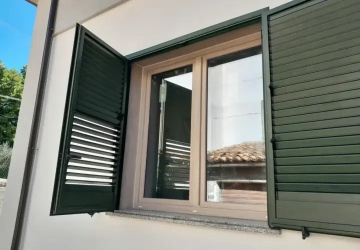 Infissi PVC effetto legno, colori naturali per un'estetica calda e moderna. Le persiane verdi si integrano perfettamente.