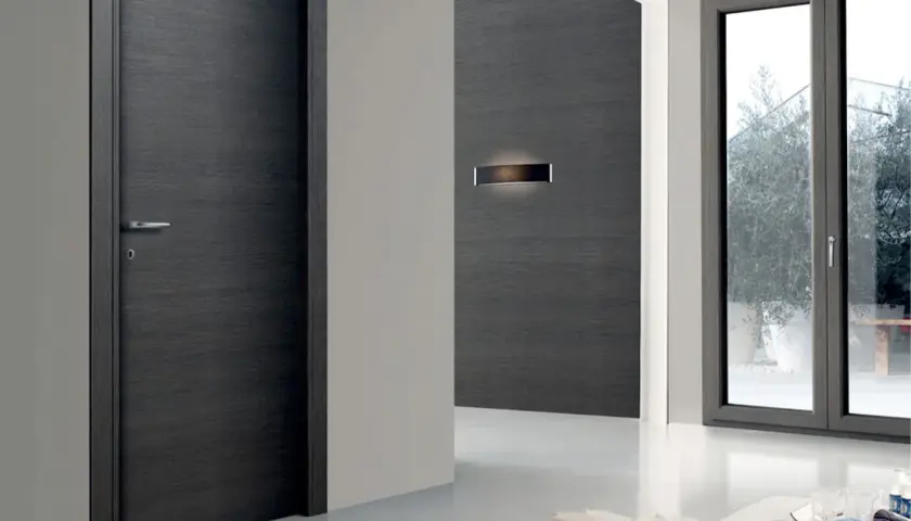 Porta moderna in legno scuro e finestra con infisso grigio. La trasmittanza termica, unità di misura fondamentale per l'efficienza energetica, è un valore da considerare.