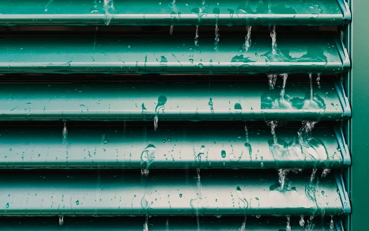 Acqua che scorre su persiane verdi, un esempio visivo per capire come pulire le persiane in ferro.