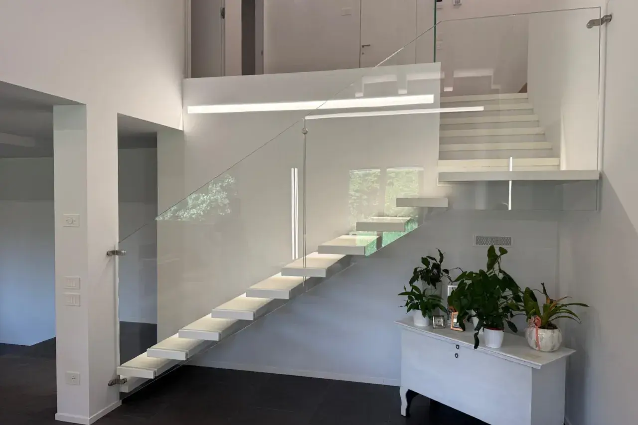 Moderna scala a sbalzo con parapetto in vetro, illuminazione integrata e un'elegante balaustra. Perfetta per il vano scale di una villa moderna.