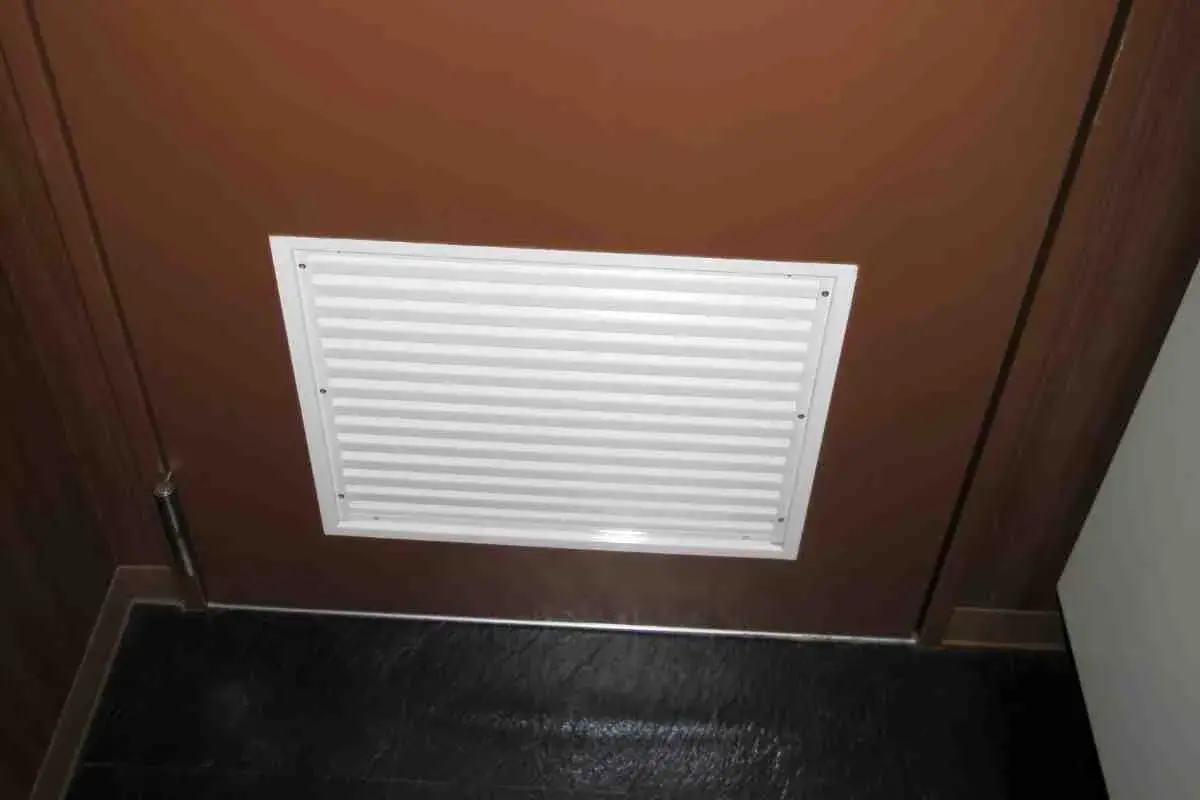 Griglia di ventilazione bianca su porta marrone, ideale per capire come arieggiare una stanza senza finestre.