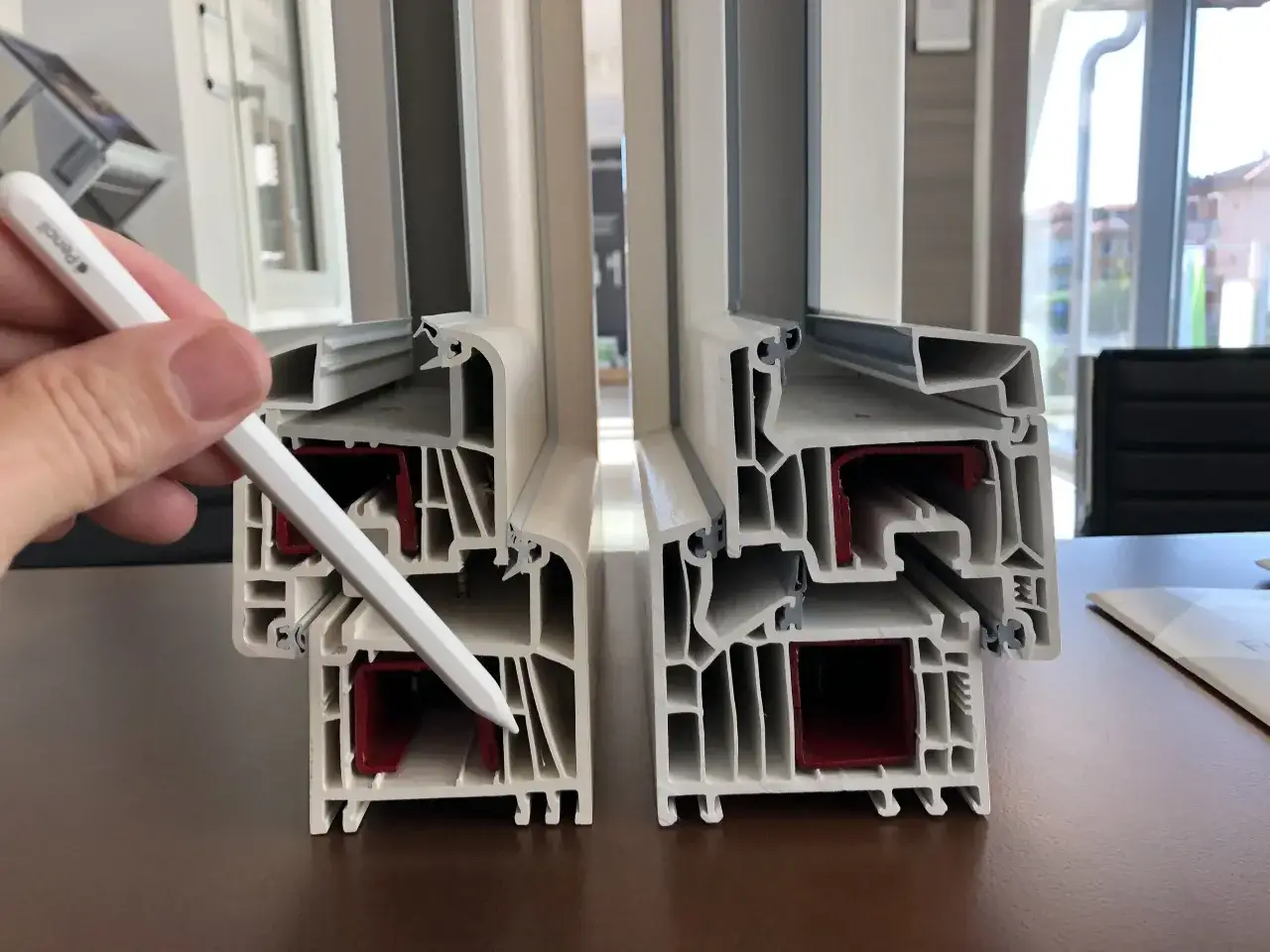 Sezione di profili per finestre in PVC, evidenziati con una penna. Si osservano le camere interne e le guarnizioni, che contribuiscono ai valori PVC di isolamento termico e acustico.