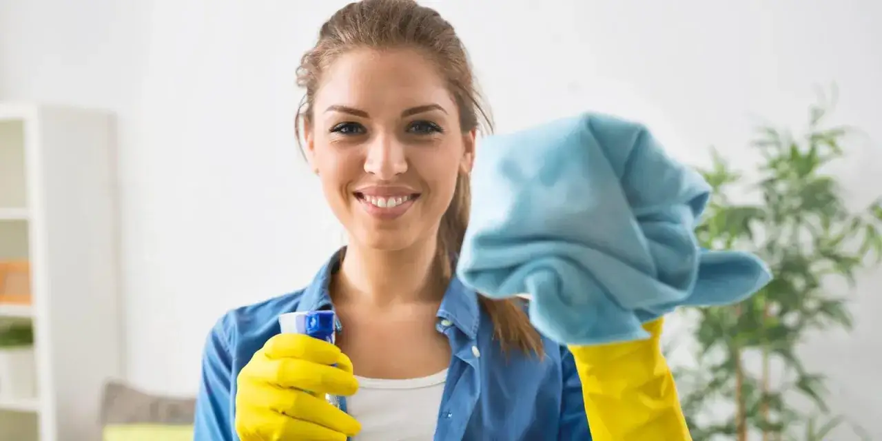 Donna sorridente con guanti gialli e panno blu, pronta a pulire la veranda del balcone.