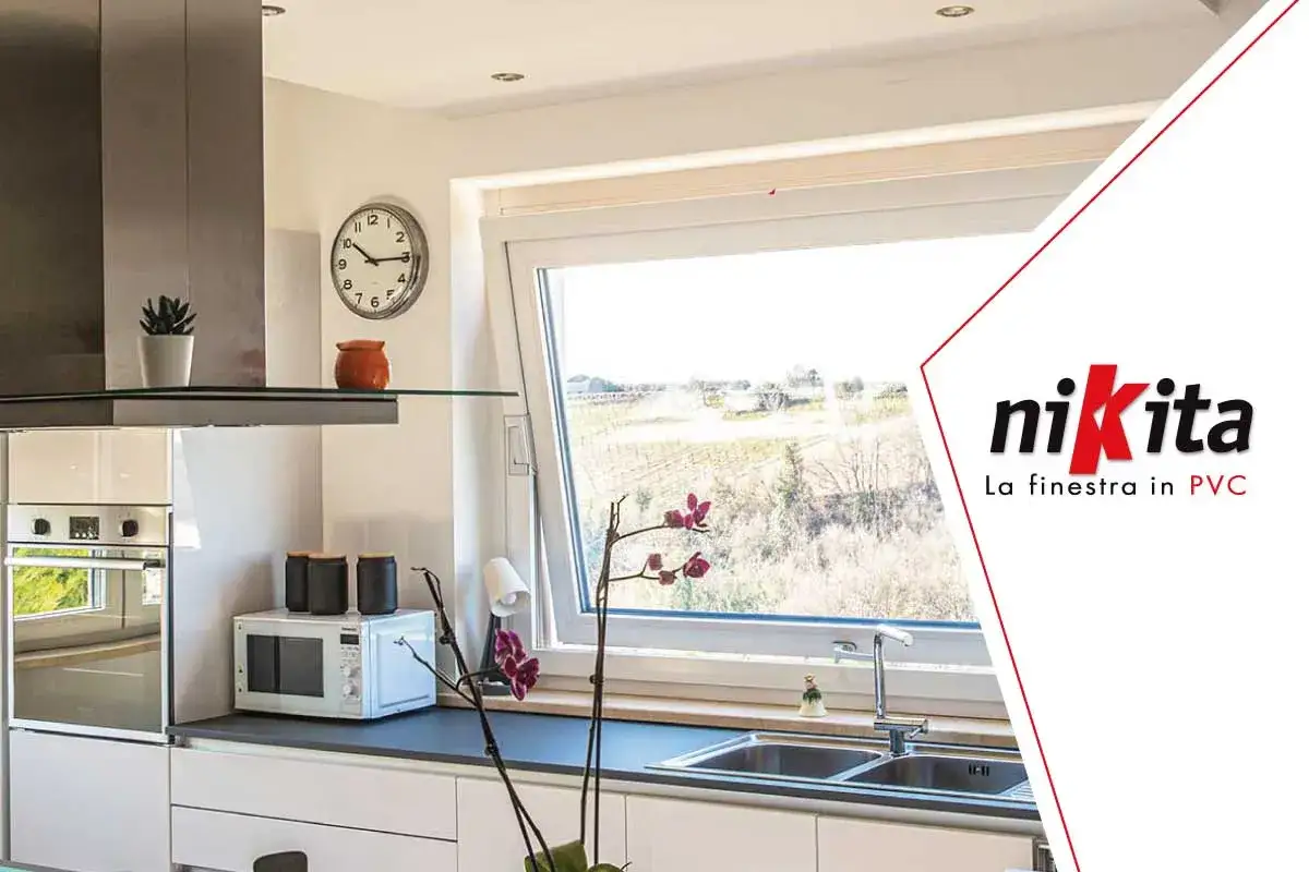 Interno cucina moderna con casa con infissi bianchi luminosa, lavello, microonde e vista sul paesaggio.
