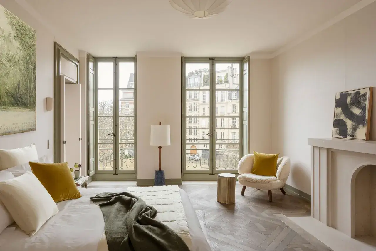 Camera da letto con letto, poltrona e camino. Le porte e gli infissi verdi creano un'armonia visiva, un perfetto esempio di come abbinare porte e infissi per un ambiente elegante.