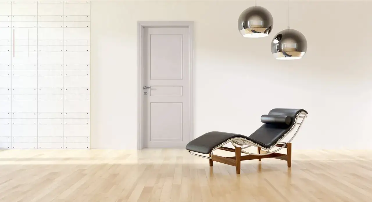 Un soggiorno moderno con porte bianche, pareti tortora, una chaise longue in pelle nera e due lampade a sospensione sferiche.