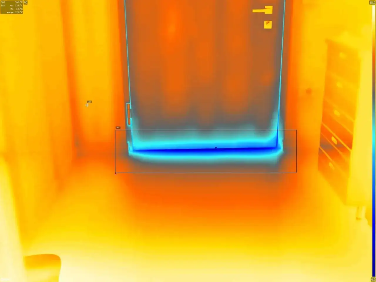 Termocamera mostra una fredda corrente d'aria in casa, visibile come una striscia blu sotto una porta.