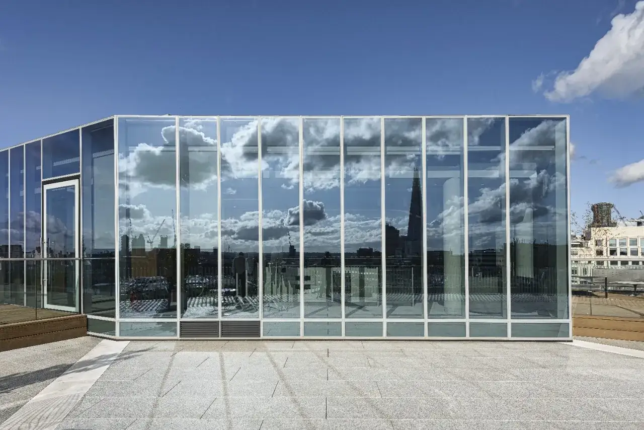 Moderne facciate architettoniche in vetro riflettono un cielo nuvoloso e lo skyline di una città, creando un gioco di luci e forme.